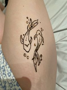 a woman's thigh with a tattoo of two fish and bubbles on the side