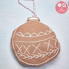 a brown ornament with white stitching on it and a red string hanging from the top