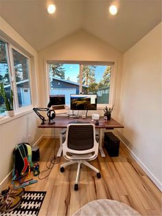 a home office with two computer monitors and a laptop on a desk in front of a window