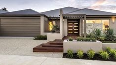 a modern house with landscaping and plants in the front yard