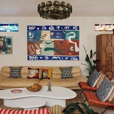 a living room filled with lots of furniture next to a painting on the wall above a coffee table