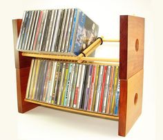 a wooden cd rack with many cds on it and a magazine holder holding the dvd's