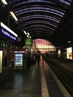 a train station with people waiting for their trains to arrive at the end of the platform