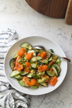 a white bowl filled with cucumbers and carrots on top of a table