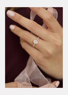 a woman's hand with a diamond ring on her finger and a ribbon around her wrist