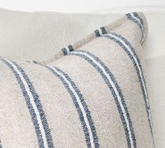 a close up of a pillow on a couch with blue and white striped linens