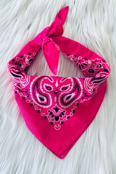 pink bandana with black and white designs on it sitting on top of a fur rug