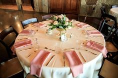 the table is set with pink napkins and place settings for guests to sit at