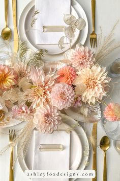 a table setting with white plates, silverware and pink flowers