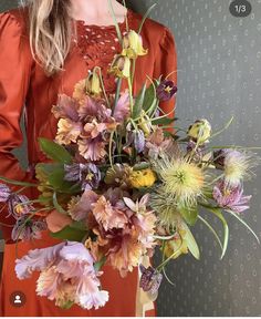 a woman in an orange dress holding a bouquet of flowers