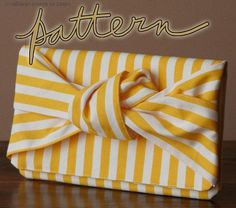 a yellow and white striped purse with a bow on the front, sitting on a wooden table