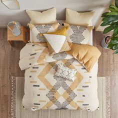 an overhead view of a bed with yellow and white comforters, pillows and blankets