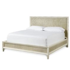 the bed is made with white linens and beige wood frame, along with pillows