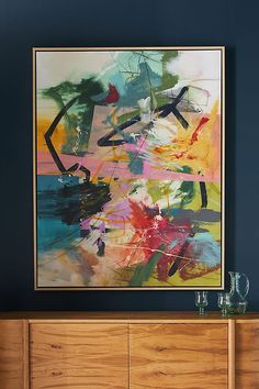 an abstract painting hangs on the wall above a dresser