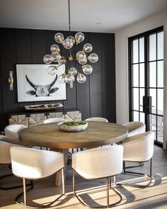 a dining room table with white chairs and a chandelier hanging from the ceiling