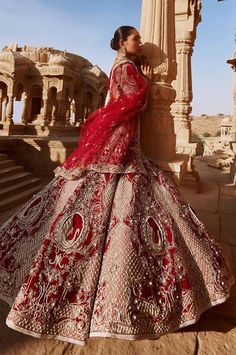 a woman in a red and white wedding dress standing on the side of a building