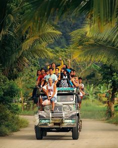 a group of people riding on the back of a truck in front of palm trees