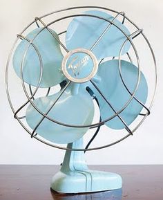 a blue fan sitting on top of a wooden table