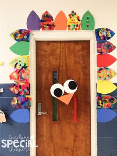 a door decorated with colorful paper leaves and a cartoon turkey on it's face