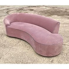 a large pink couch sitting on top of a cement floor next to a stone wall