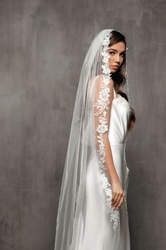 a woman in a white wedding dress with a veil on her head and flowers on the side