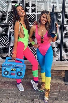 two women dressed in colorful outfits posing for the camera, one holding a boombox