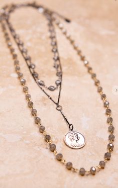 a necklace with a coin on it sitting on top of a marble table next to a chain