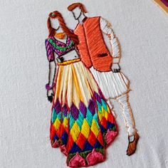 a man and woman in colorful clothing are embroidered onto a piece of white linens