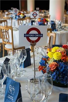 the table is set up for an event with flowers and place settings on it,