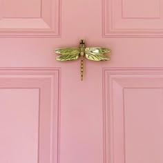 a pink door with a yellow dragonfly on it's side and the bottom part of its wings