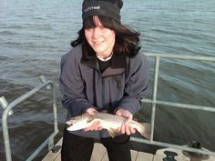 a woman standing on a boat holding a fish