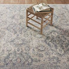 an old rug with a book on it and a wooden chair in the middle is shown