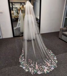 a bridal gown is on display in front of a mannequin wearing a veil