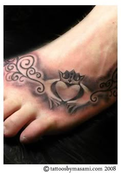 a foot with a heart and crown tattoo on it's side, next to a black cat