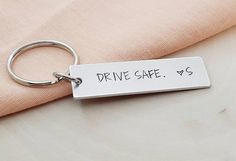 a metal keychain that says drive safe is on top of a pink cloth