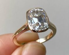 a close up of a person's hand holding a ring with a large diamond in it