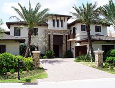 a large house with palm trees in front of it and a driveway leading to the entrance