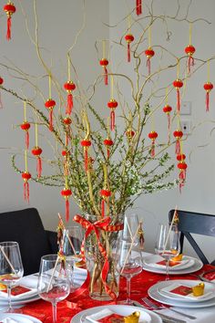 the table is set with red and white plates, silverware, and vases