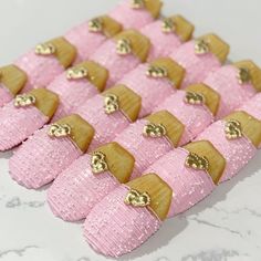 pink and gold decorated cookies are arranged in rows on a white tablecloth with gold accents