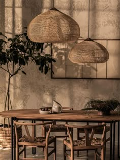 a dining table with four chairs and three hanging lights above it in front of a plant