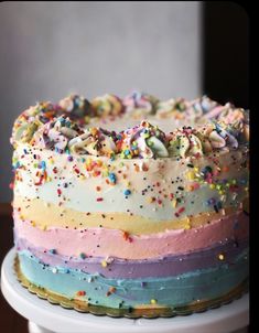 a multicolored cake with sprinkles on it sitting on a table