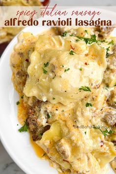 a white plate topped with lasagna covered in cheese and meat sauce next to bread