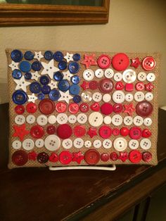 an american flag made out of buttons is displayed on a table in front of a mirror