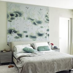 a white bed sitting in a bedroom next to a painting on the wall above it