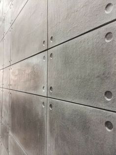 the side of a building with holes in it's concrete wall and one person walking by