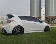 a white car parked in front of two silos