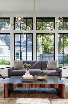 a living room filled with lots of furniture and large windows in the wall behind it