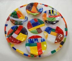 multicolored glass plate with spoons on white surface