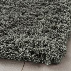 a close up view of a rug on the floor with grey carpet and wood floors