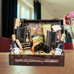 a wooden box filled with lots of different types of wine and cheeses on top of a table